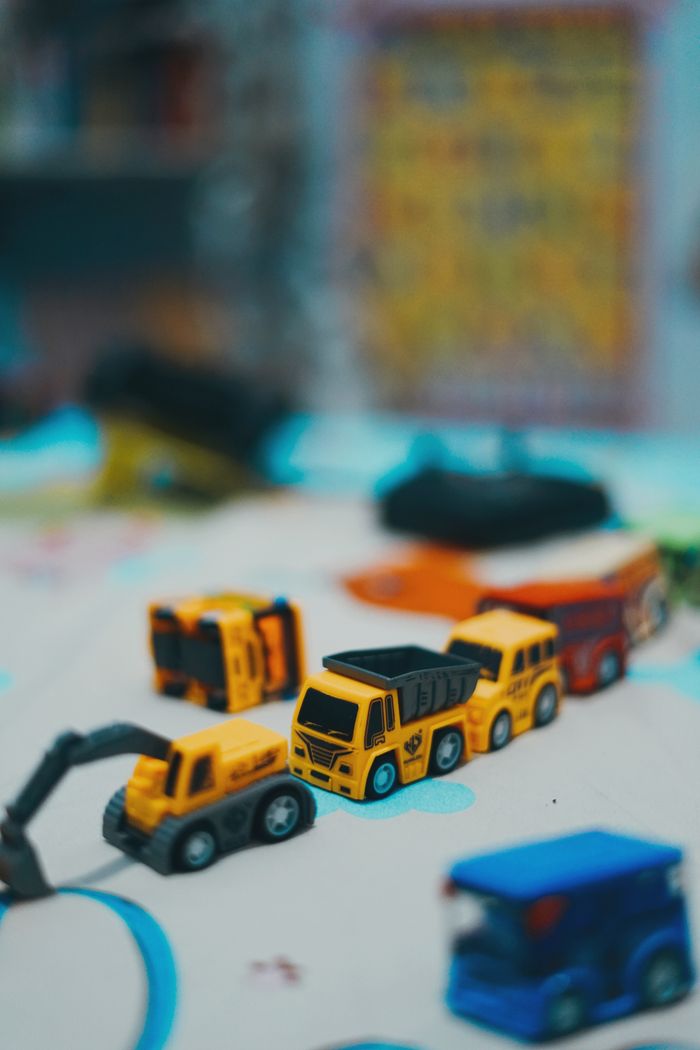 services-01 A collection of toy construction trucks on a play mat, showcasing vibrant colors and details.