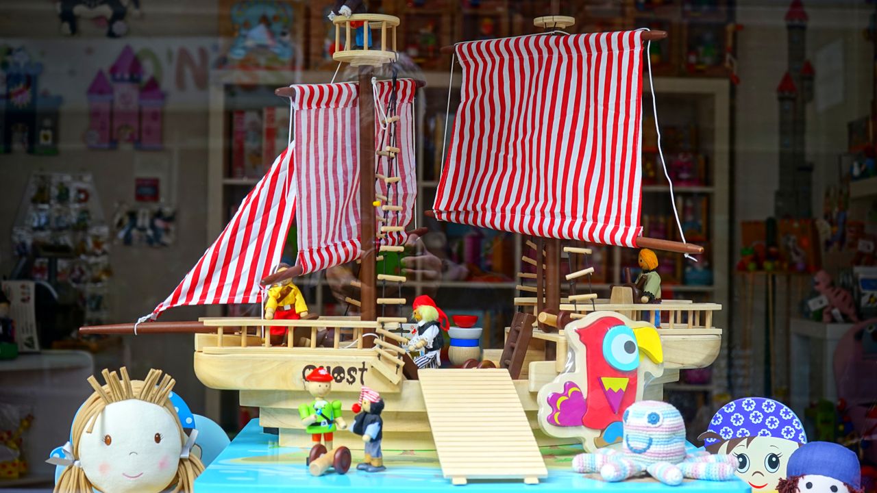 team-01 Vibrant toy shop window featuring a wooden ship and colorful stuffed animals.