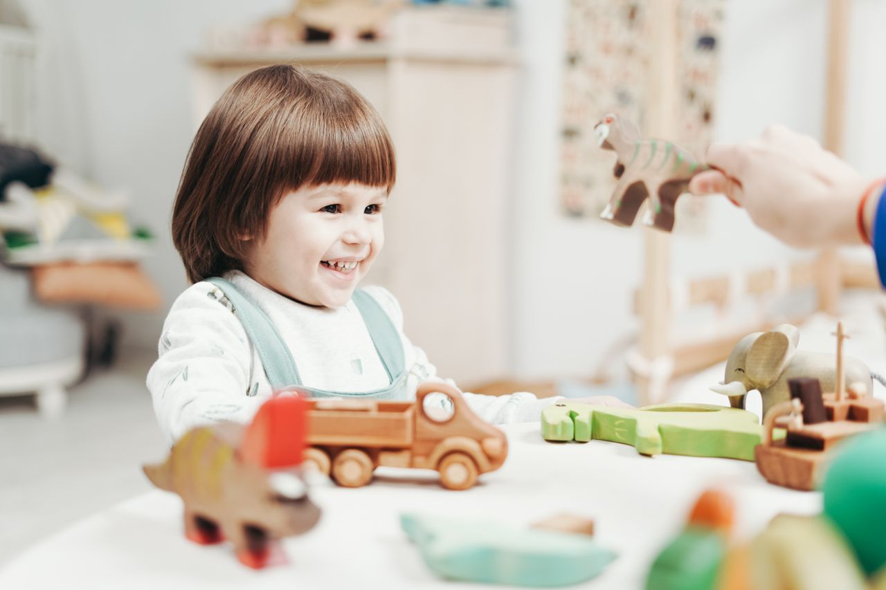 team-03 A joyful child plays with wooden toys, showcasing creativity and happiness indoors.