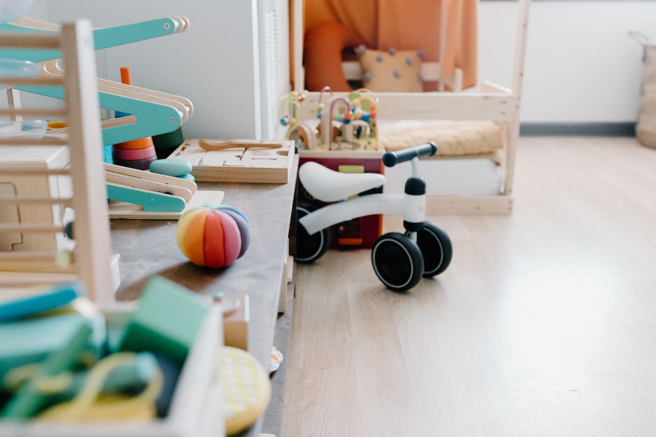 services-03 Bright and minimalistic children's playroom featuring wooden toys and balance bike for sustainable learning.